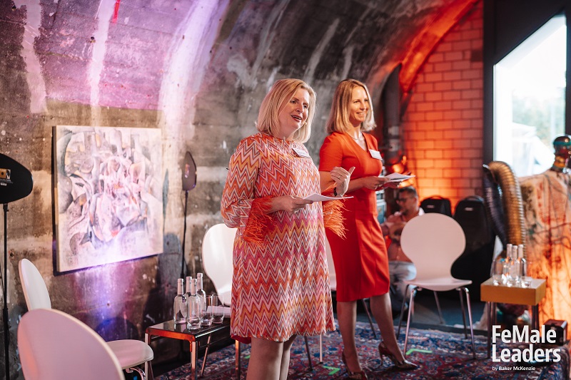 Two females in colorful outfits hosting an event
